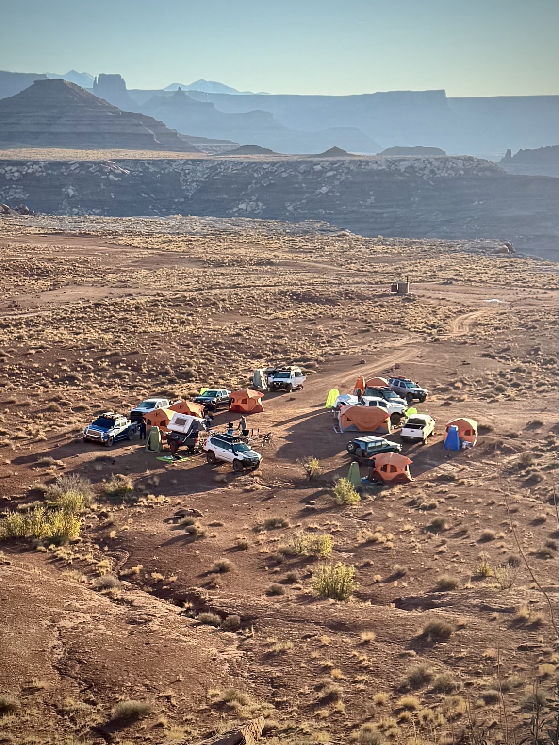 Overland vehicles and tents gathered at a desert canyon campsite