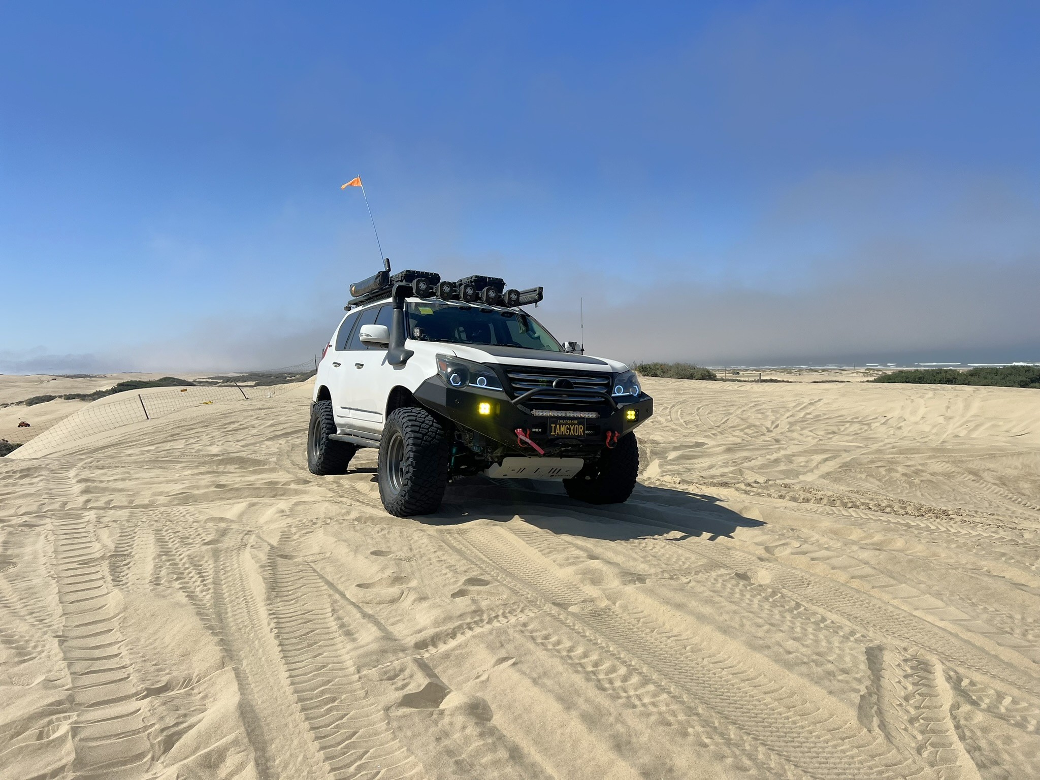 White overland vehicle exploring open coastal sand dunes